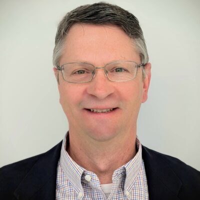 Photo of Rob Crouthamel wearing glasses, black sport coat, and light plaid dress shirt.